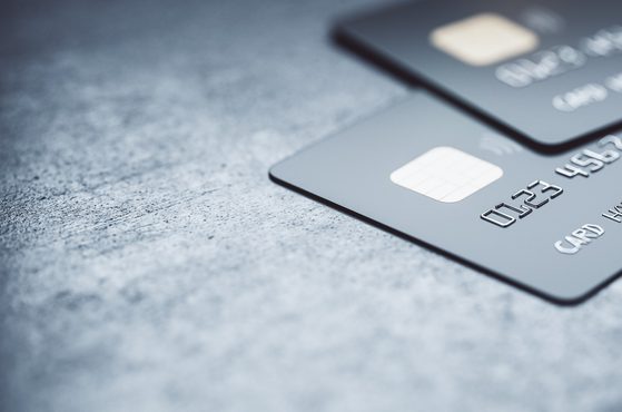 Online payments concept with black credit cards on abstract blank dark surface