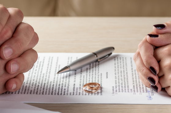 A divorcing couple sits across a table with divorce papers