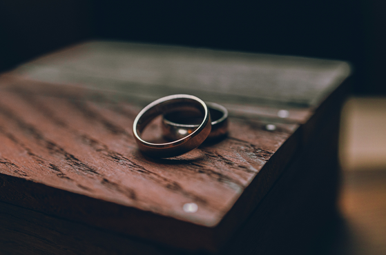 Two silver rings resting on a weathered wooden surface, with a blurred background, possibly on a desk or table.