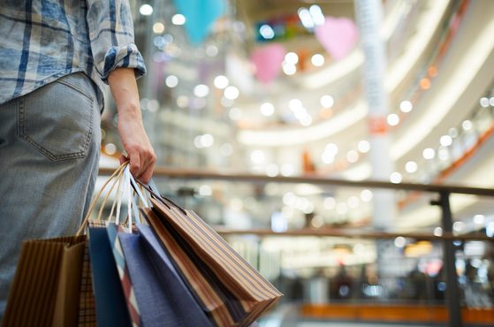 A customer holds multiple shopping bags in a shopping mall