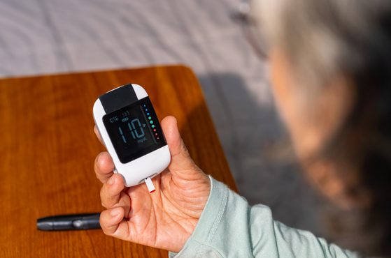 A person holds a medical device checking their blood sugar level