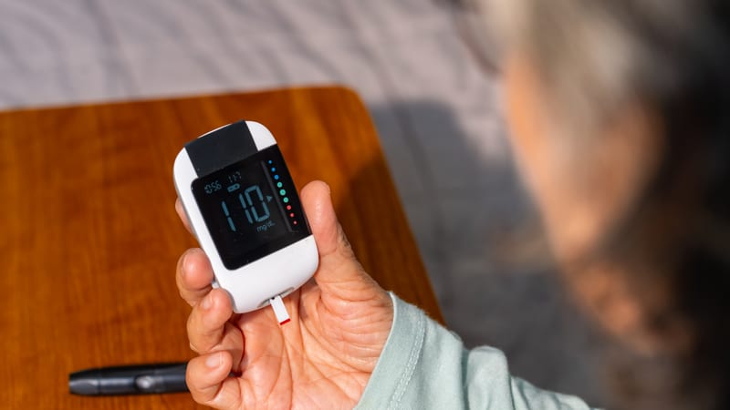A person holds a medical device checking their blood sugar level