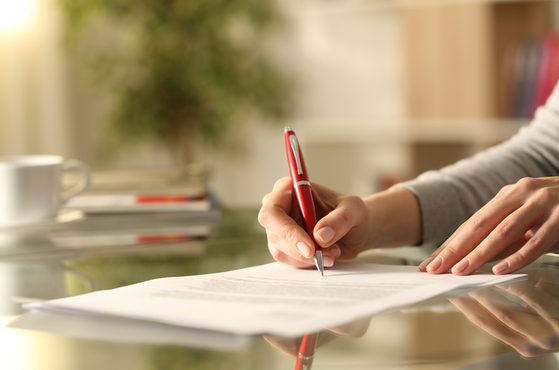 A senior executive signs a settlement agreement with a red pen