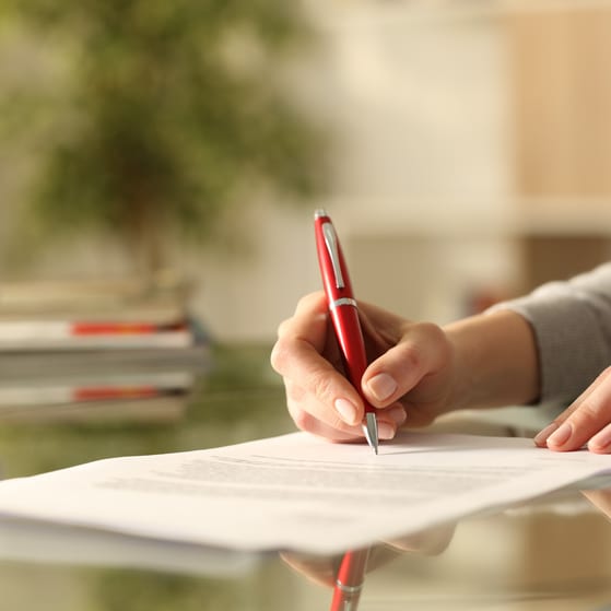 A senior executive signs a settlement agreement with a red pen