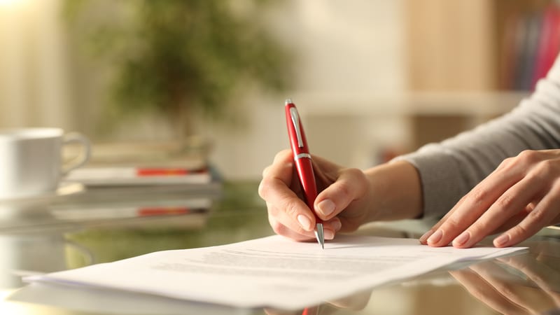 A senior executive signs a settlement agreement with a red pen