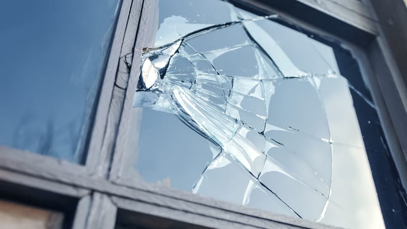 A smashed window which has been damaged by antisocial behaviour