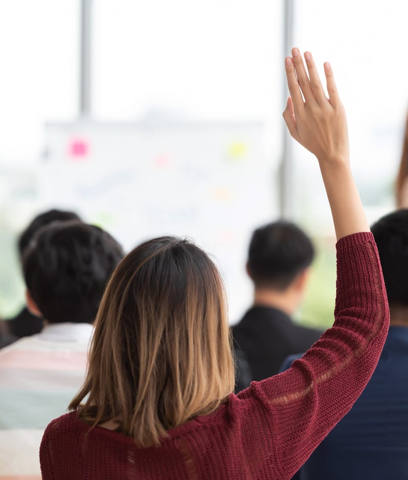 A student raises their hand in a training seminar