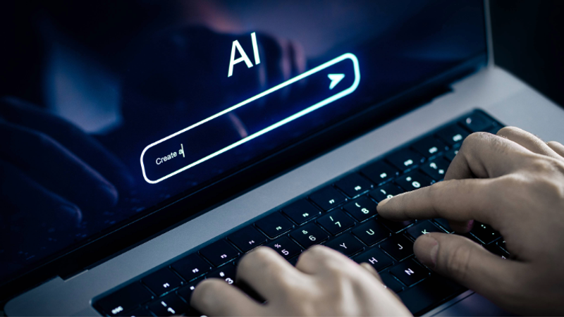 Hands typing on a laptop keyboard with a screen displaying a search bar labelled "AI" and a "Create" button, in a dark setting.
