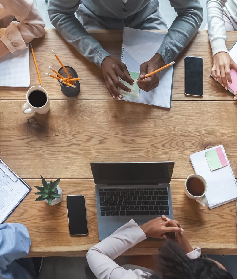 An aerial view of a group of employees collaborate around a table to agree a decision