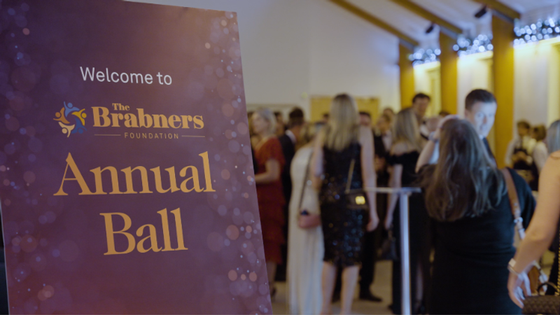 Purple sign reads Welcome to The Brabners Foundation Annual Ball as formally dressed guests mingle in a well-lit reception hall