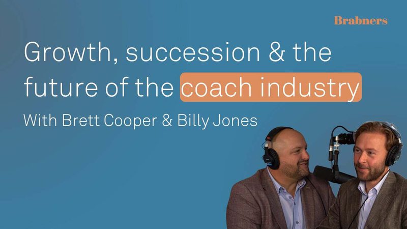 Blue backdrop with large white text about growth and the coach industry; two suited individuals wearing headphones speak into a microphone, Brabners logo top right.