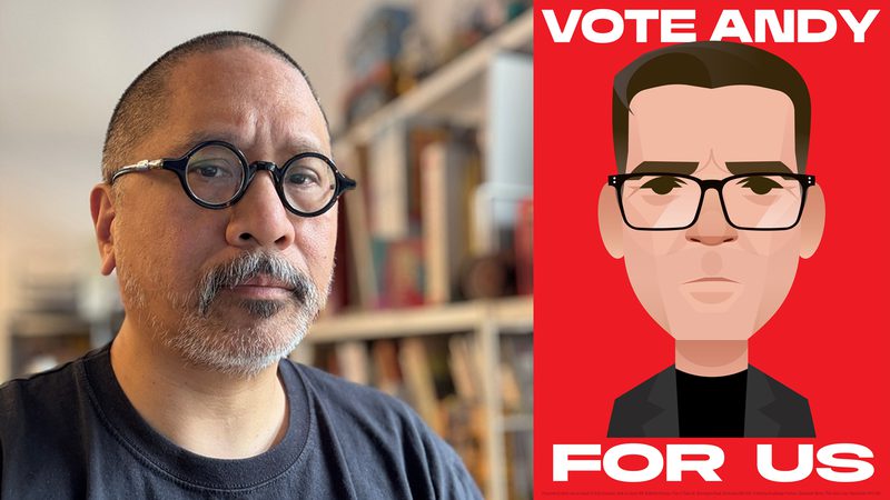 A person with round black glasses and grey beard sits indoors with shelves behind; on the right a red poster shows a cartoon portrait and reads "VOTE ANDY FOR US".