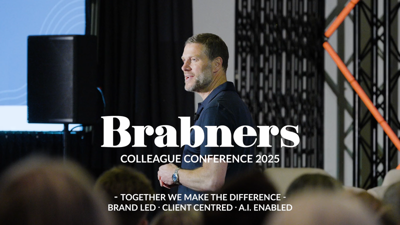 Brabners colleague speaking at a conference with a presentation screen behind, attendees’ heads visible in the foreground.