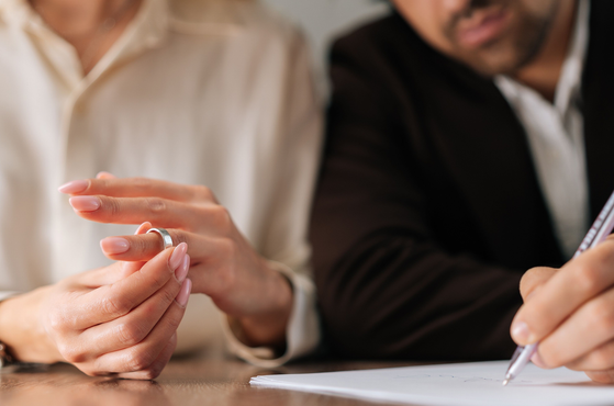 Divorcing couple sign papers and remove their rings