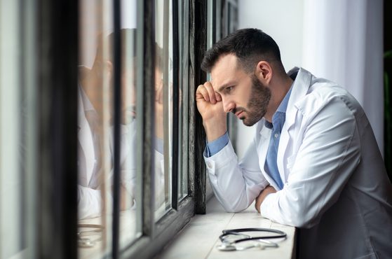 Doctor looking our window looking distraught