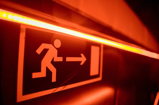 A red illuminated emergency exit sign with a running figure and an arrow pointing to the right.