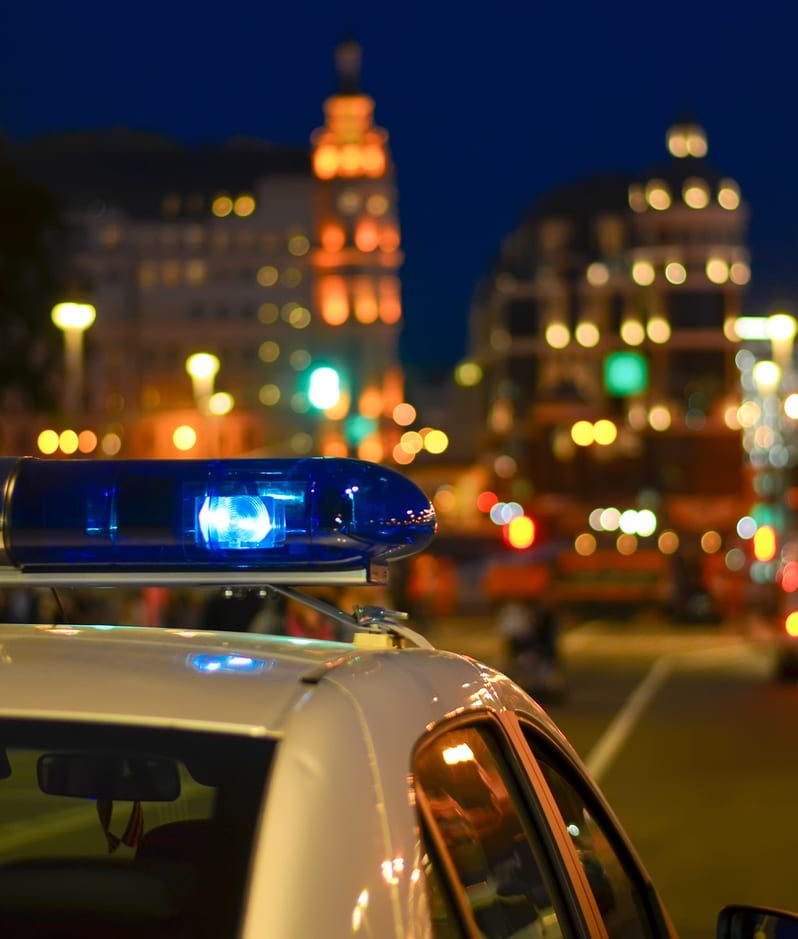 Flashing police car siren with busy city backdrop