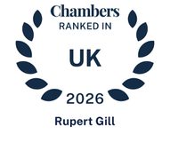 A badge with a laurel wreath and text reading "Chambers ranked in UK 2026 Rupert Gill" in dark blue on a white background.