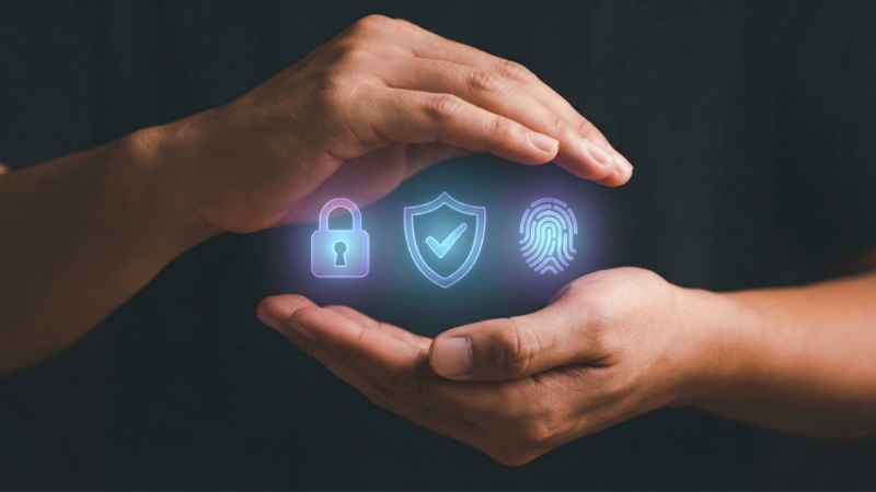 Two hands cradle glowing icons: a padlock, a shield with a check, and a fingerprint, symbolising security, privacy and biometric protection.