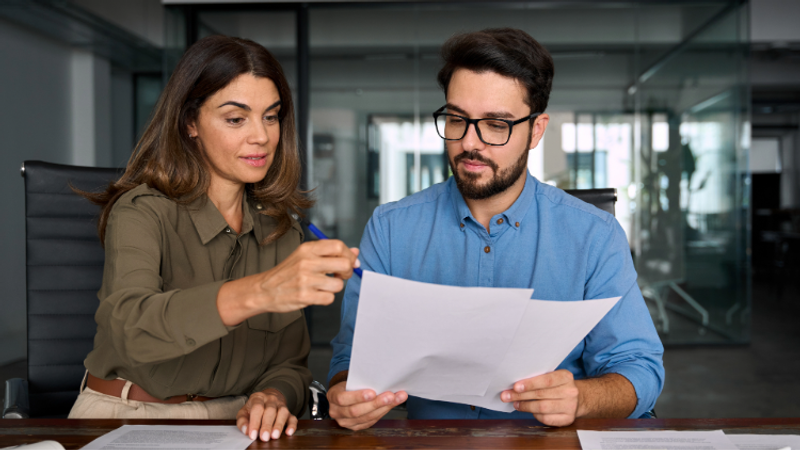 Two colleagues reviewing documents together in a modern office environment.