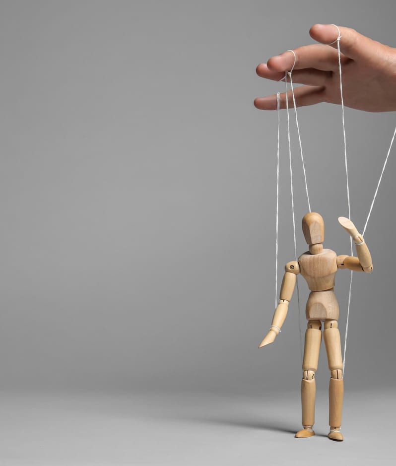 Man pulling strings of puppet on gray background
