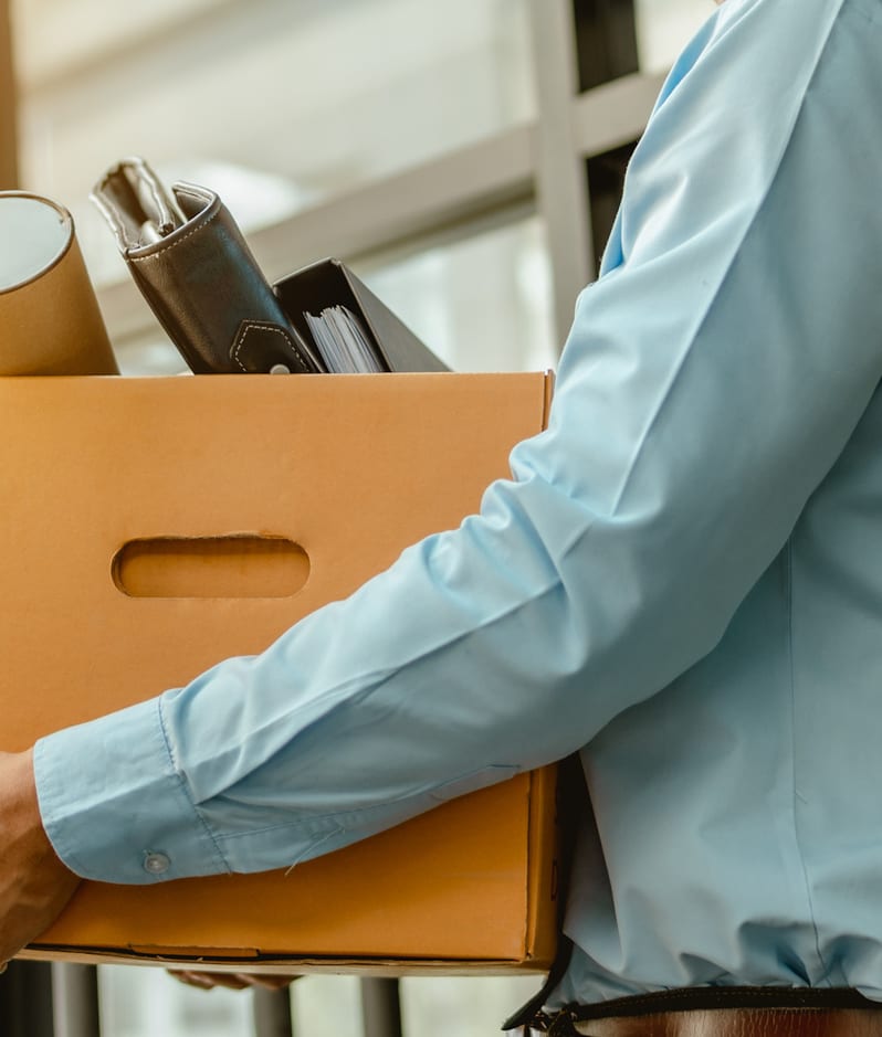 Man taking box of items from office desk resigning concept