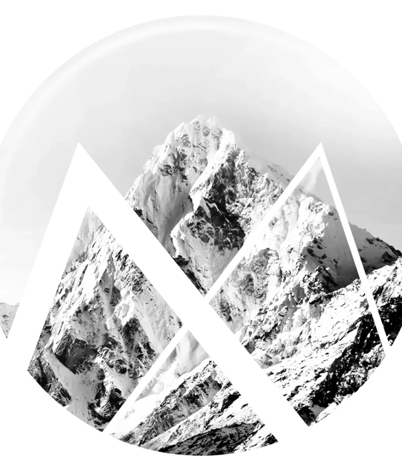 A black and white image of snow-covered mountain peaks with rugged, sharp edges and steep slopes.