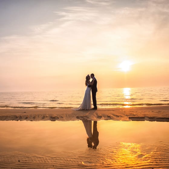 Newly married couple embracing on beach 2