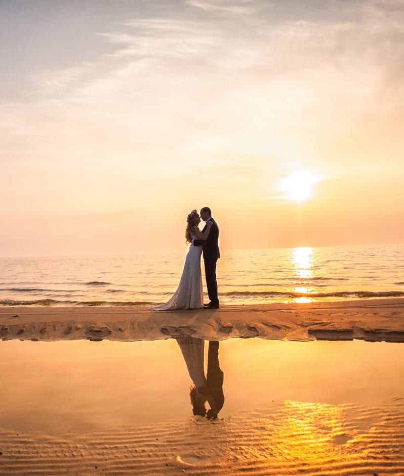 Newly married couple embracing on beach 2