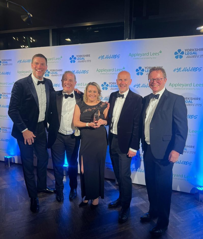 Five people in formal attire smiling at the camera at an awards event, with a backdrop displaying "Yorkshire Legal Awards 2022" and "Appleyard Lees."