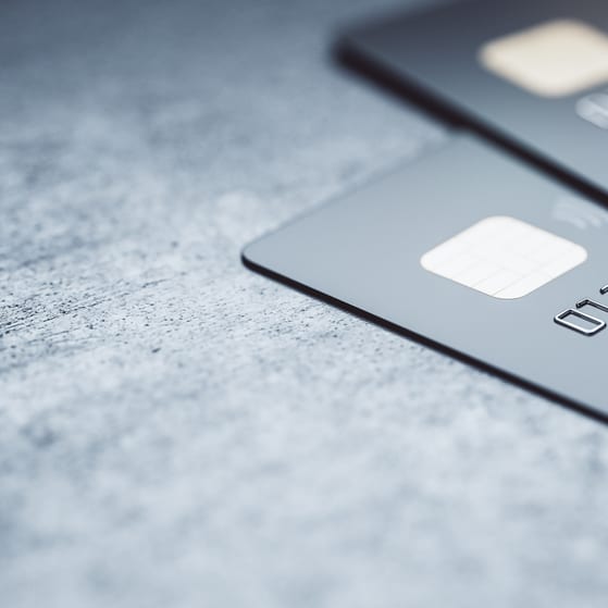 Online payments concept with black credit cards on abstract blank dark surface