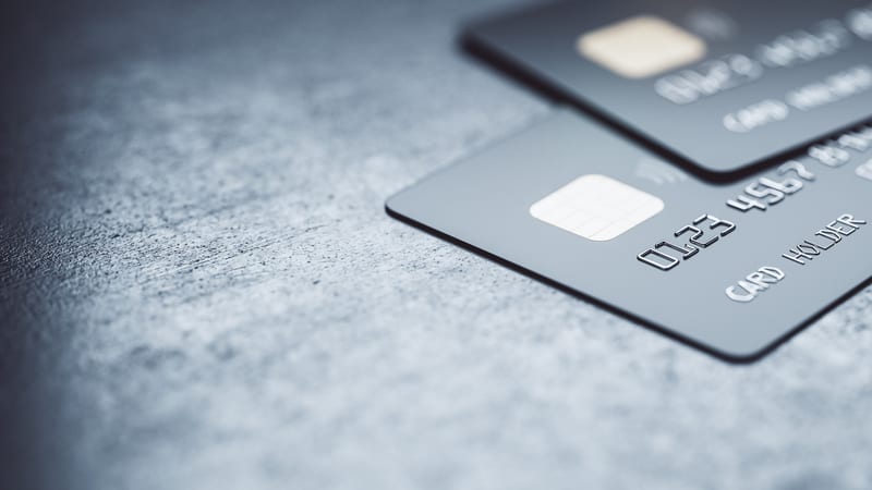 Online payments concept with black credit cards on abstract blank dark surface