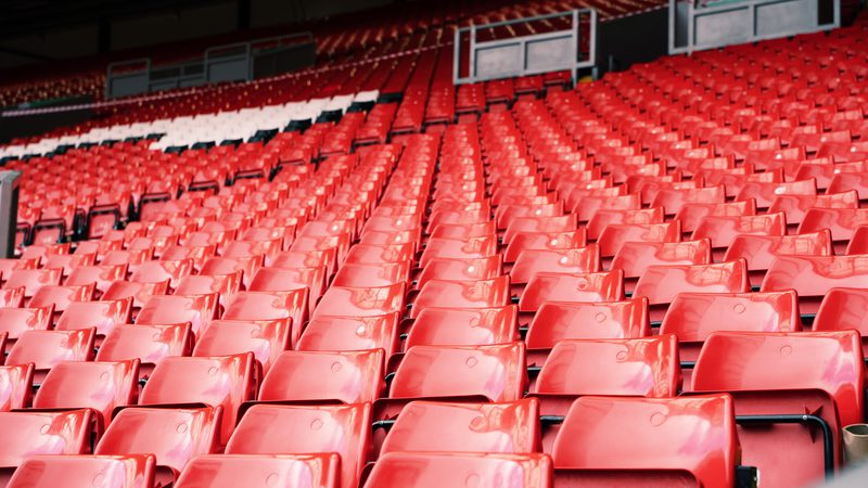 Empty red stadium seats arranged in rows under a covered area.