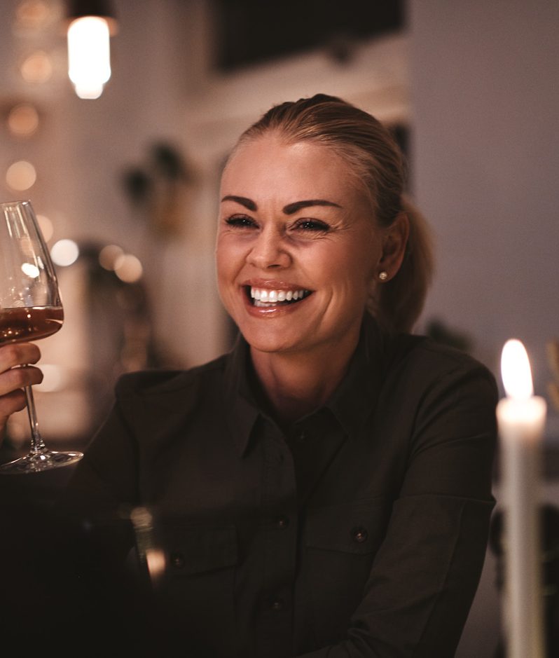 Smiling woman at dinner holding wine glass
