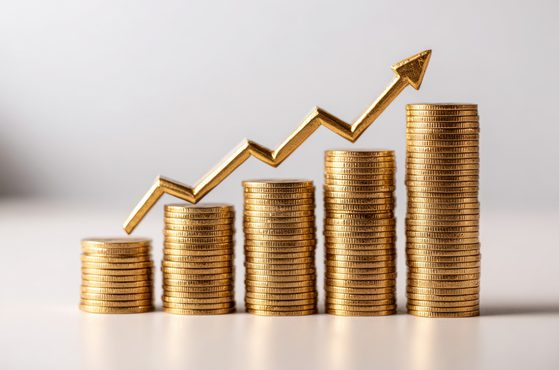Stacks of gold coins increasing in size with an arrow showing growth