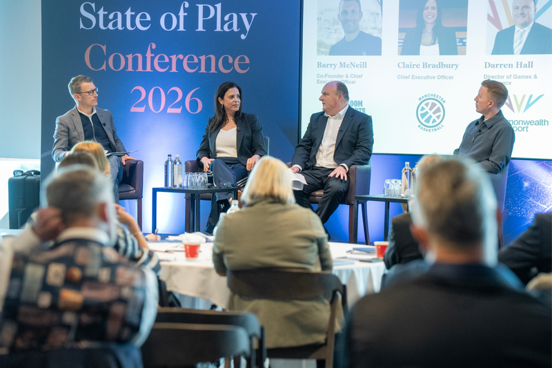 Panel discussion at the State of Play Conference 2026 with four panelists seated on stage beneath a blue backdrop, audience visible in the foreground.