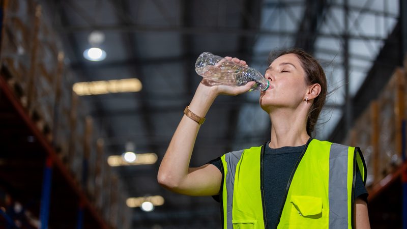 Woman construction warehouse worker drinking from water bottle