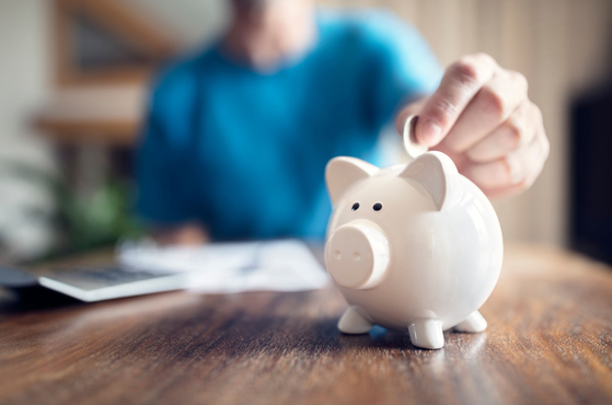 A man puts money into a piggy bank pension concept