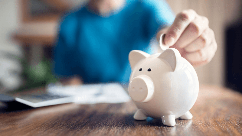 A man puts money into a piggy bank pension concept