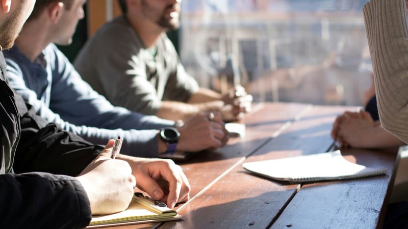 Directors sit at a table and discuss setting up a competitor business
