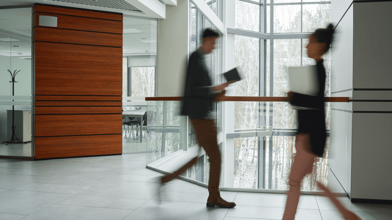 Colleagues walk past each other in an office