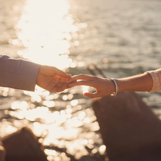 Couple holding hands at sunset by water