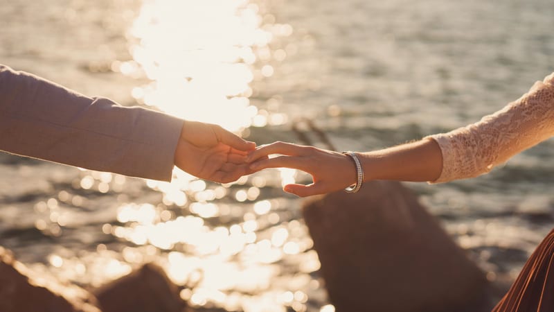Couple holding hands at sunset by water
