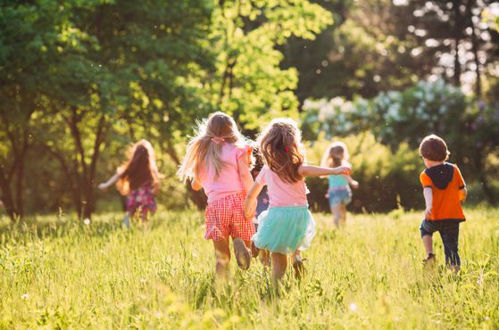 Children playing in the sunshine under a tree