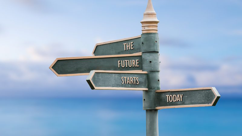 A signpost with four arrows pointing in different directions against a beach background, reading "The Future Starts Today."