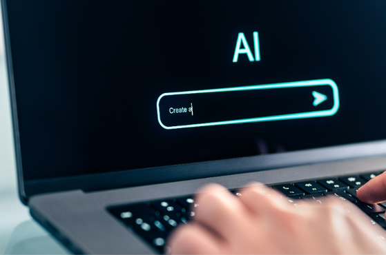 A laptop screen displays an AI interface with a text box starting with "Create a" and a hand typing on the keyboard. The screen has a dark background with neon blue accents.