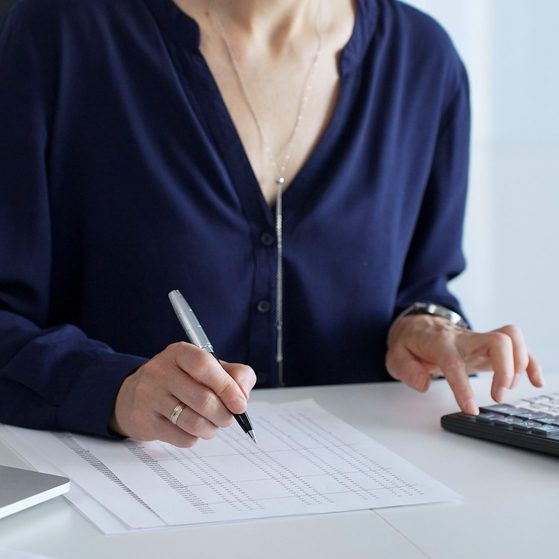 Accountant using calculator and writing notes