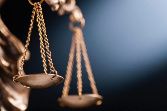 Close-up of a gold balance scale with empty, shallow pans and chain links, set against a dark background.