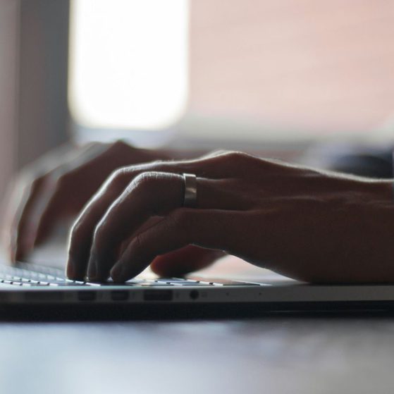 Close-up of hands typing on a laptop keyboard with a blurred background.