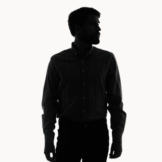 A silhouette of a man in a button-up shirt and gloves, standing against a bright, evenly lit background with no visible facial features.